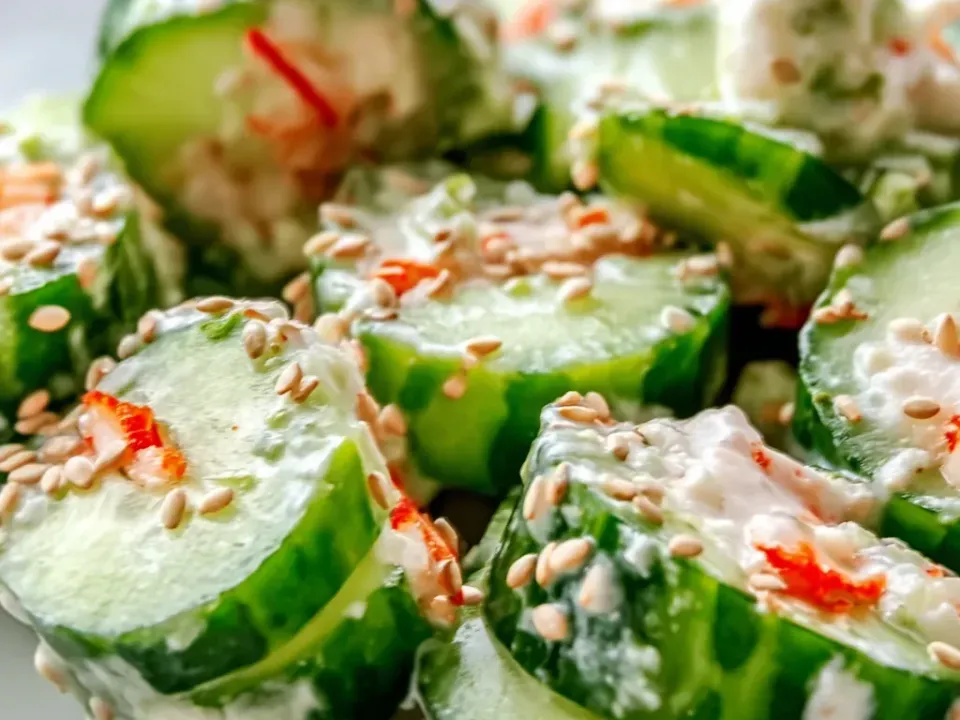 Thick cucumber rounds coated in a creamy dressing with sesame seeds and orange-red imitation crab pieces
