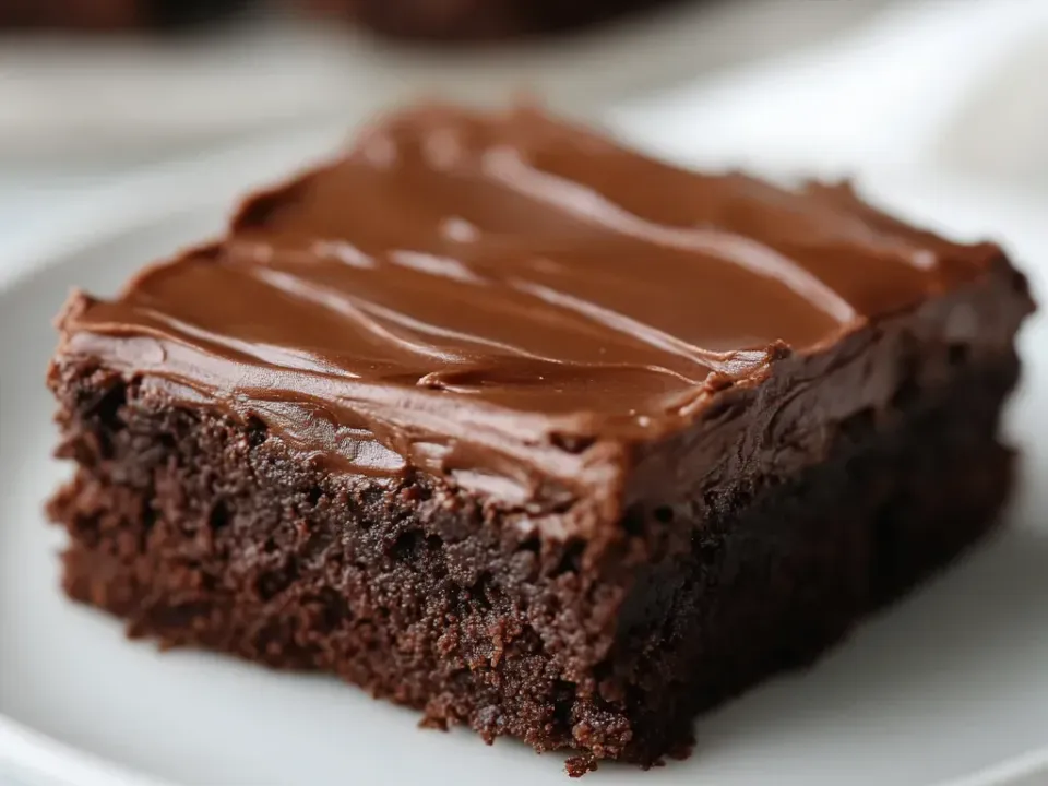 A thick square of fudgy chocolate brownie with a smooth glossy poured chocolate frosting