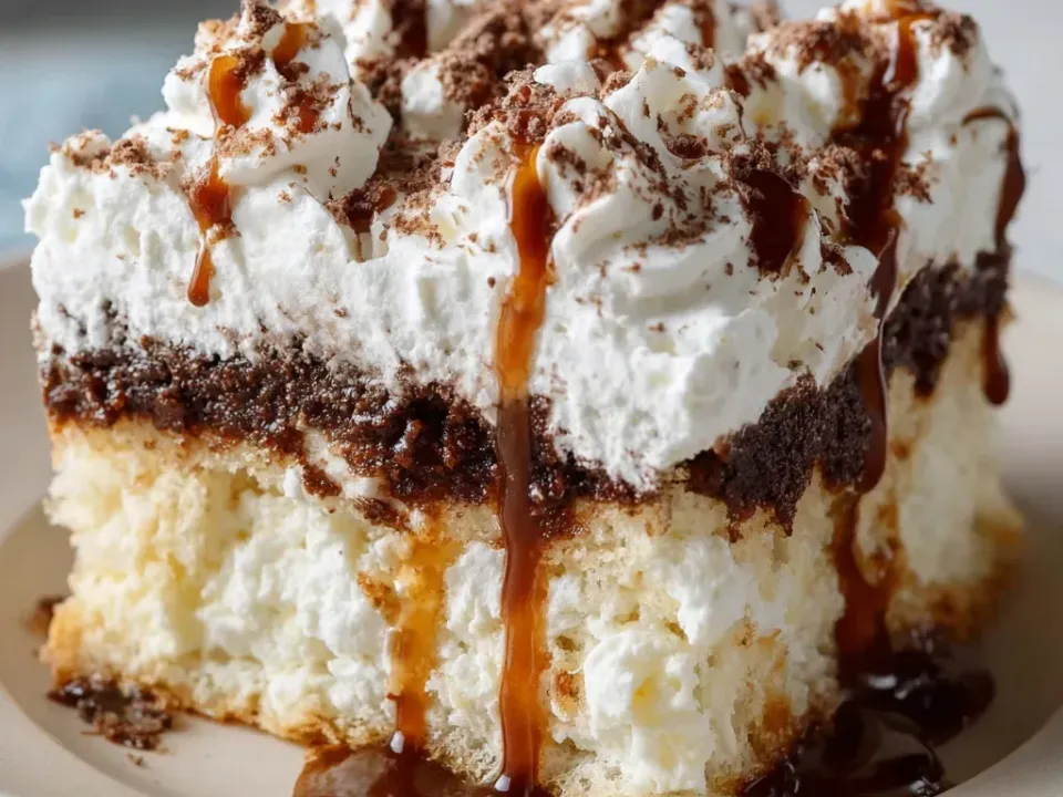 A square of white poke cake with a coffee-chocolate soaked layer, a thick whipped cream top, cocoa and a caramel-coffee drizzle