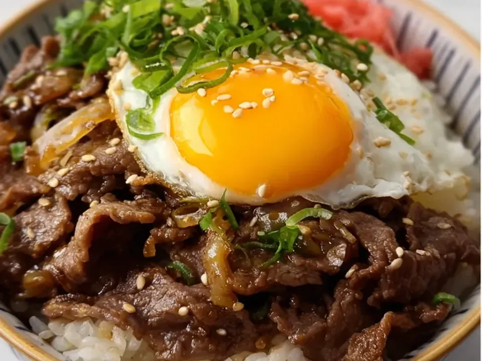 A bowl of white rice topped with thin simmered beef and onion, a soft egg, green onion, sesame seeds and pickled ginger